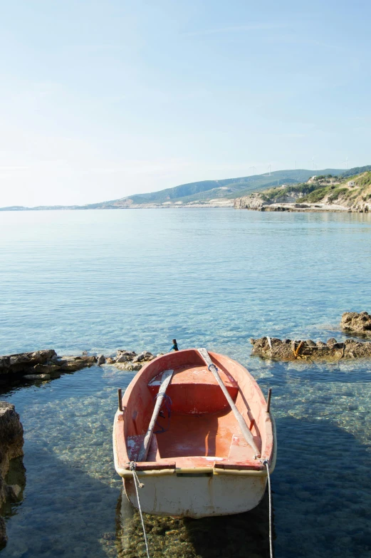 a red boat sitting on top of the water near shore