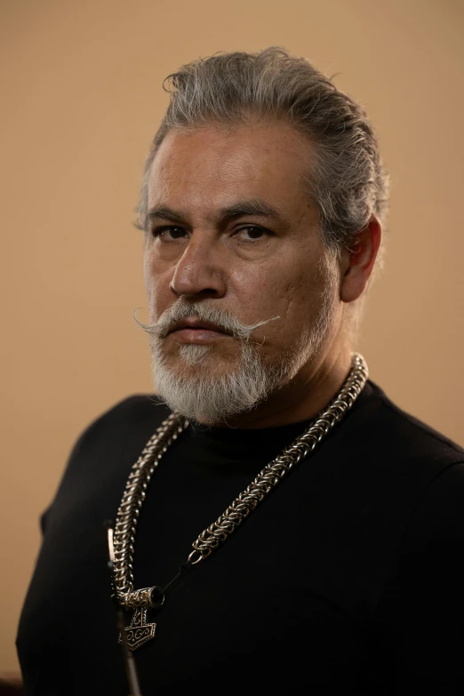 a man with silver hair and a chain on his neck
