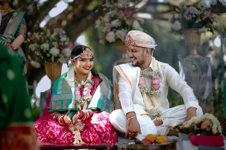 two indian brides sit side by side at their wedding