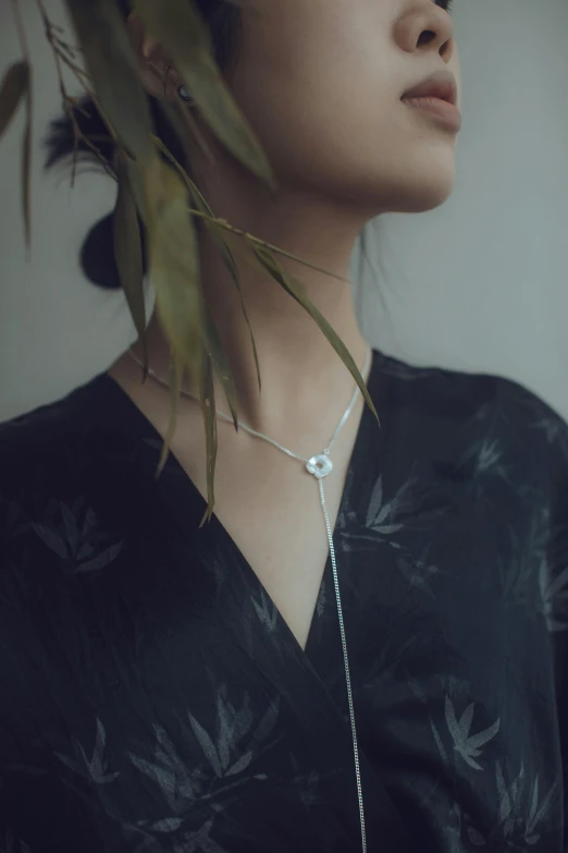 a woman with a necklace and leaves on her neck