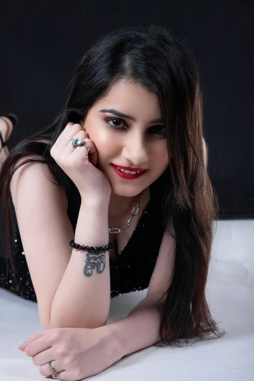 a woman in a black dress laying down with a red lipstick and diamond watch