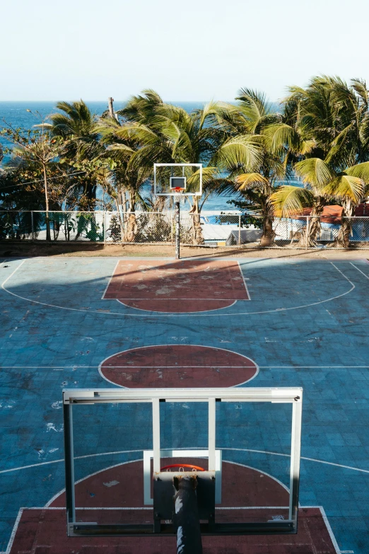 a basketball court with several hoops and the view of the beach