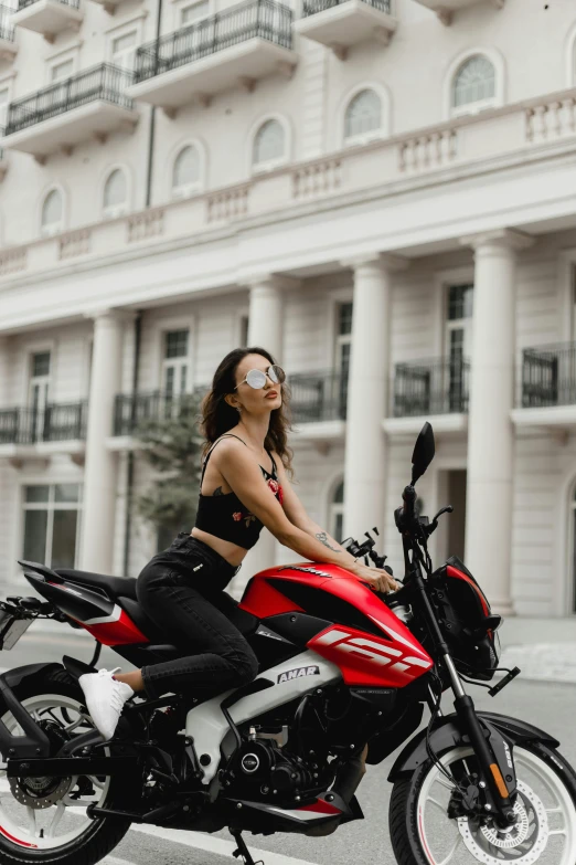 a woman is sitting on her motorcycle outside