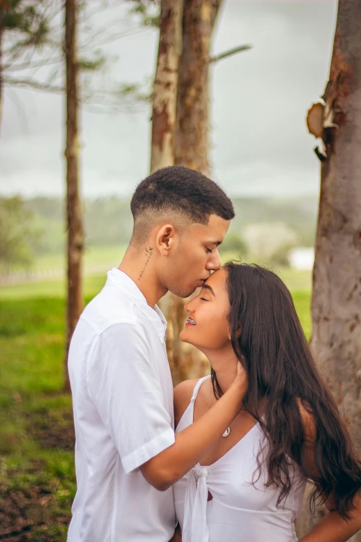 a young man and woman are kissing in the forest