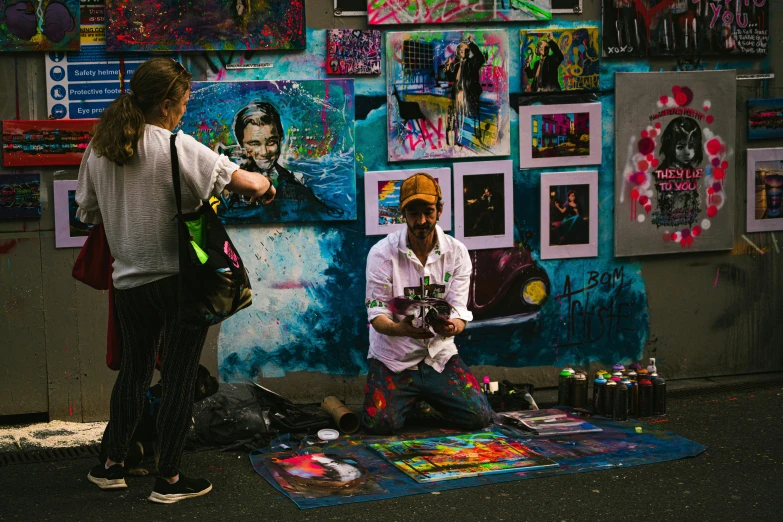 two people standing by a wall with pictures of clowns