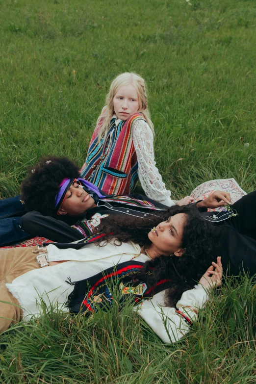 three females lying in the grass, one with a scarf