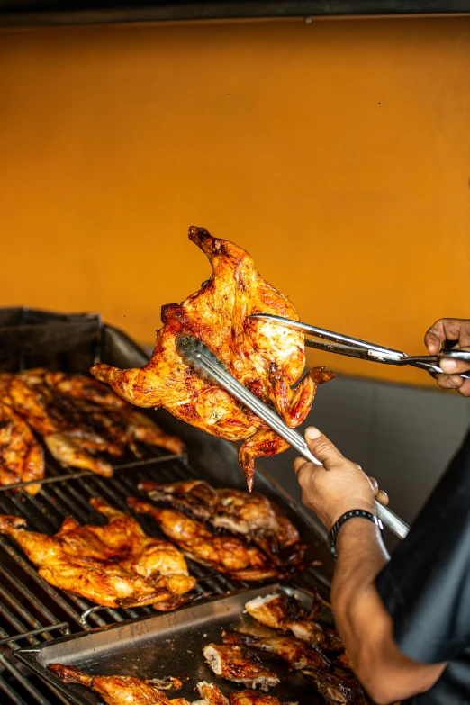 a man  pieces of chicken on top of a grill