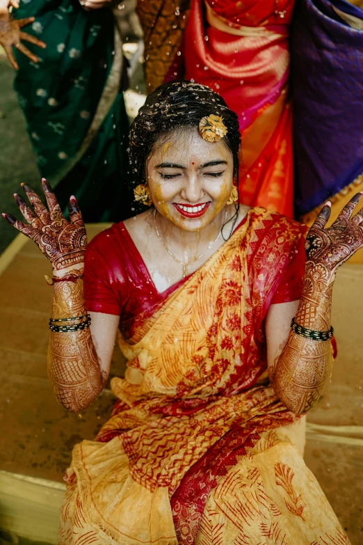 a woman is smiling in yellow saree and red blouse