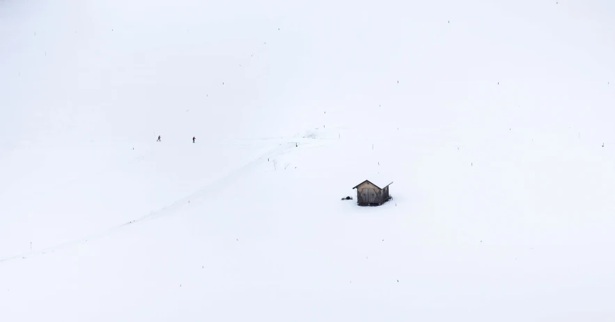 a small gray house surrounded by snow and trees