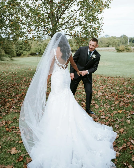 a bride and groom stand together in the leaves after their wedding