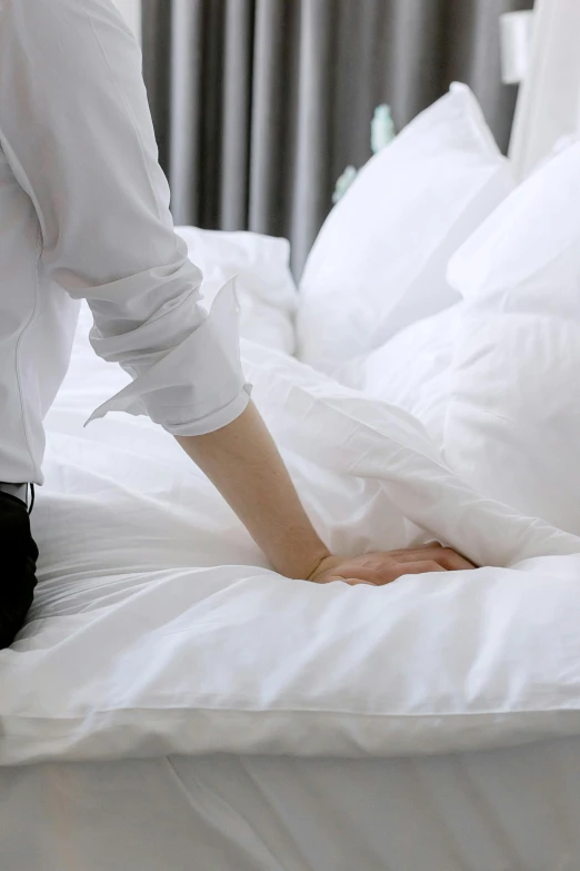 a person is pulling up sheets off a bed