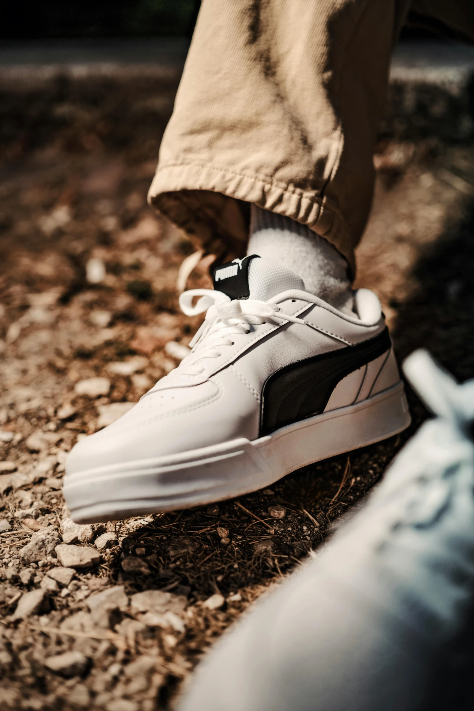 a person with white shoes standing in the dirt