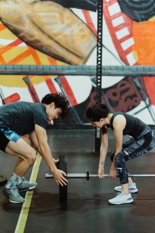 two people doing squats on top of bars