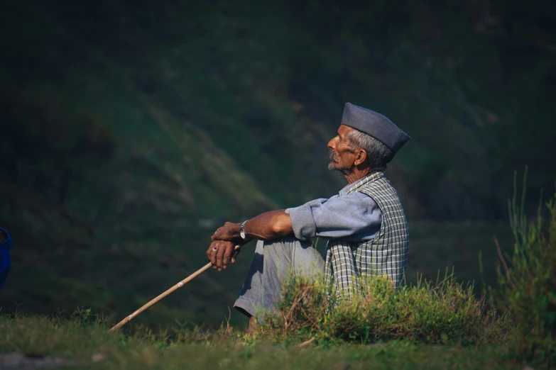 an older man is sitting on the grass