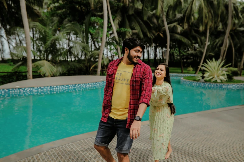 a couple stand by a swimming pool for a picture