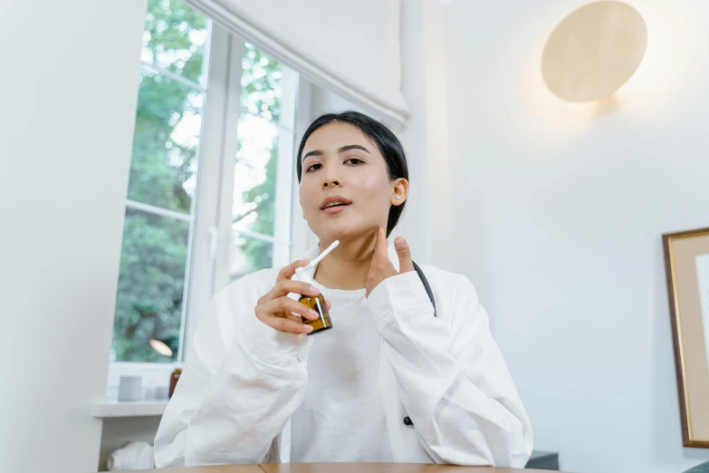 a woman wearing a white coat holding a small pill