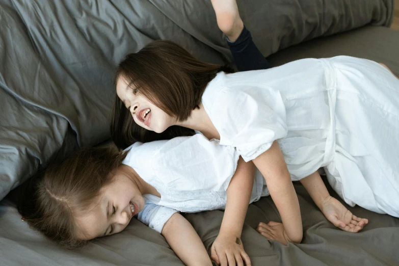 a girl and boy on a couch next to a pillow