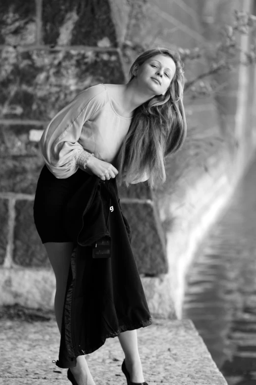 a woman leaning against a wall near water