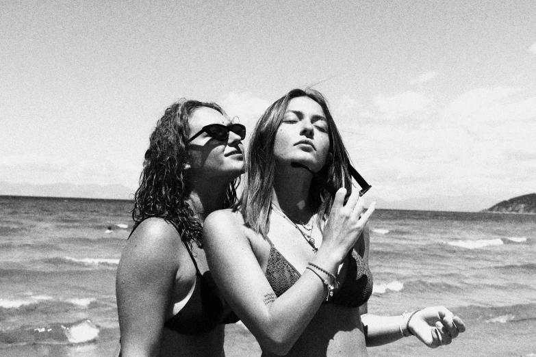 two girls standing next to each other near the ocean