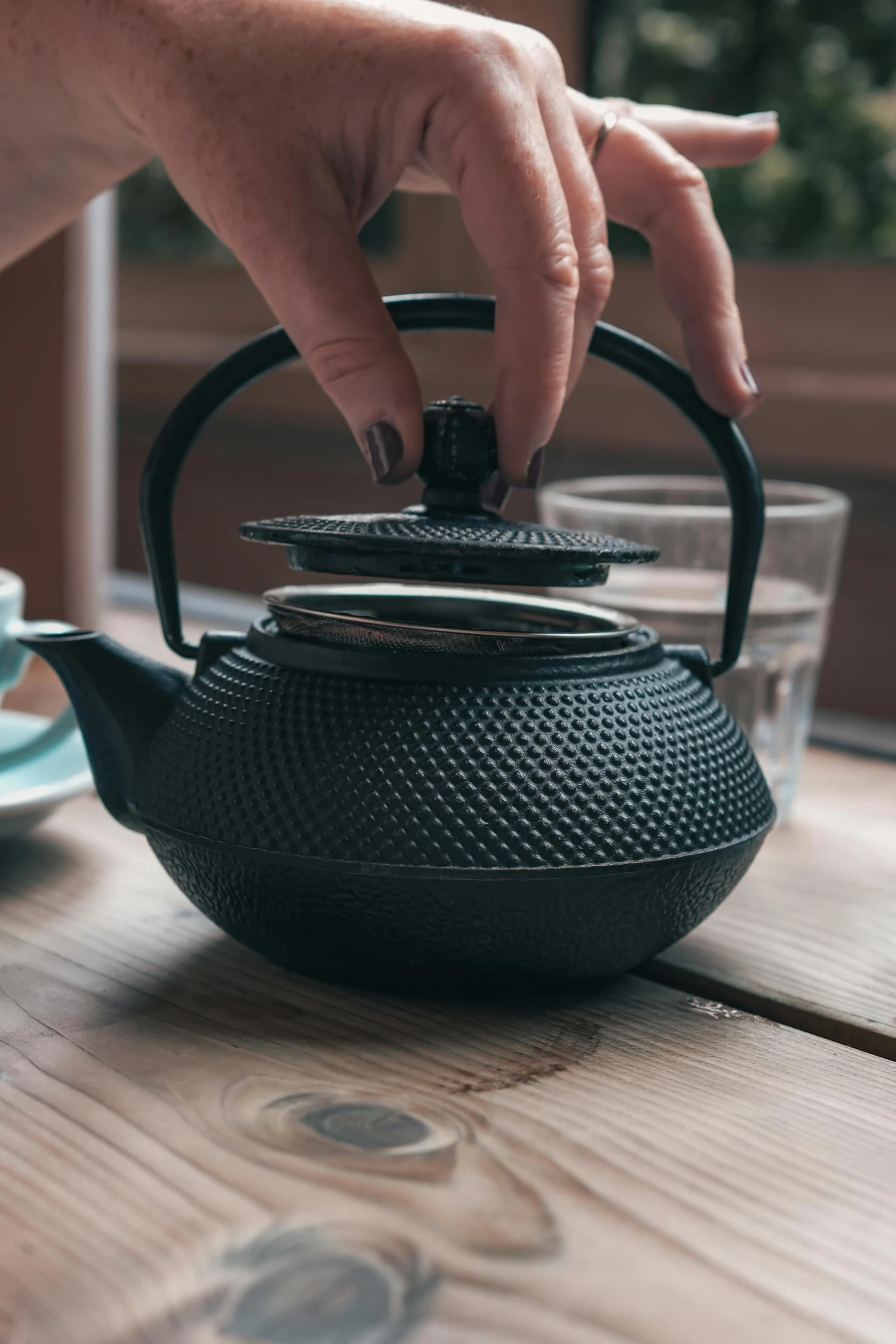 a person has their fingers in the teapot with water on the table