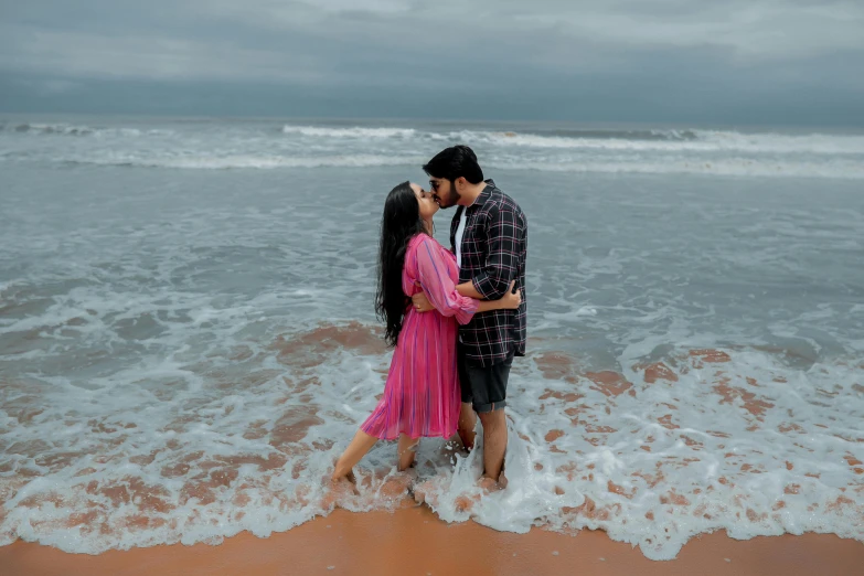 man and woman kissing in water next to shore