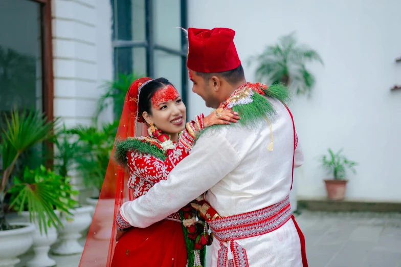 man in red is smiling as a woman hugs him