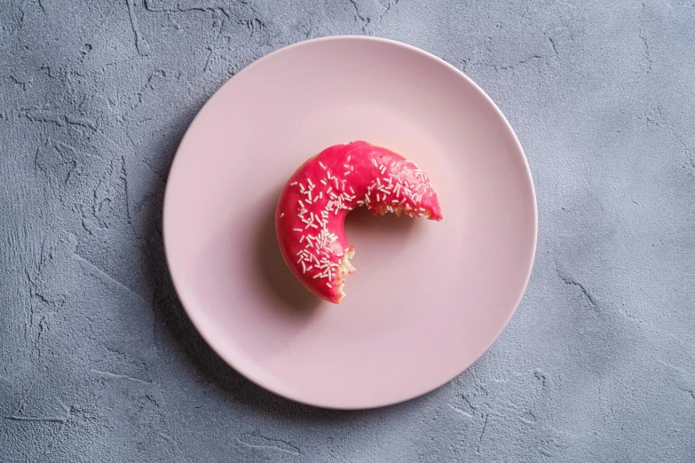 a donut on a pink plate with sprinkles and powder