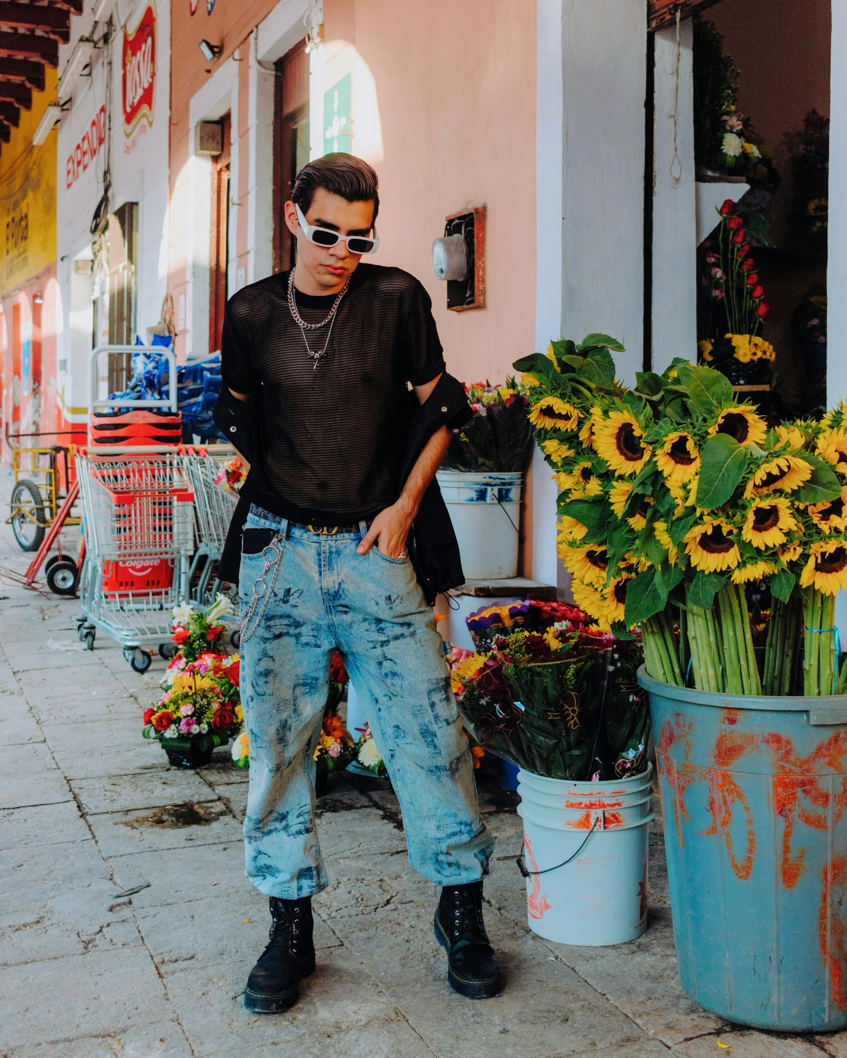 the young man is standing next to several large flowers