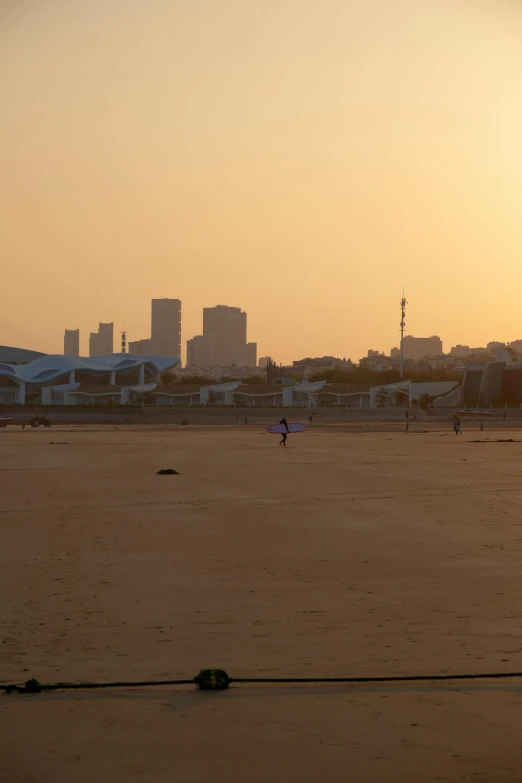 a plane sitting in a sandy beach near a city