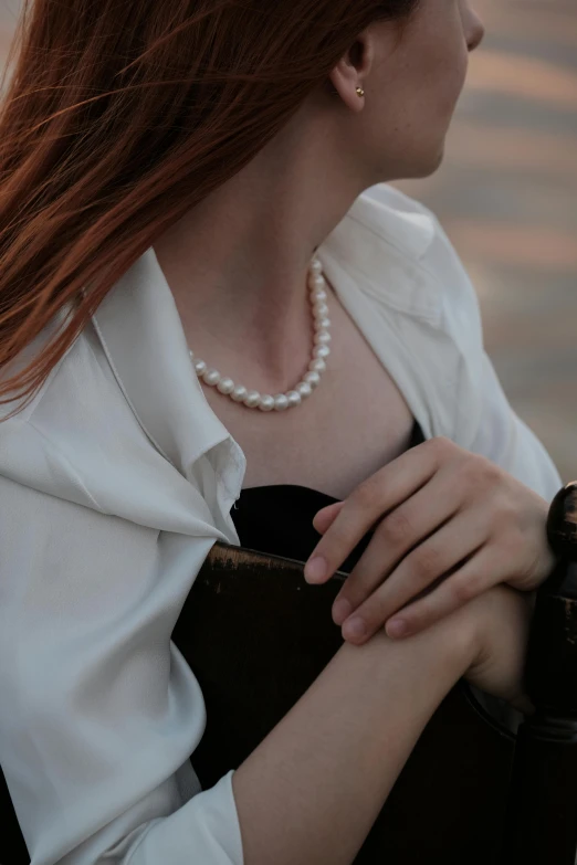 a woman holding a black purse is standing near the water