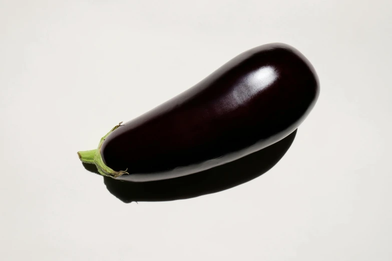 an eggplant with only one slice removed, shown in front of a white background