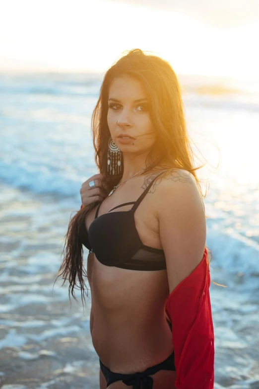 a woman posing next to the ocean wearing a black 