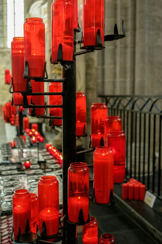 many lit candles are standing in rows on the shelf