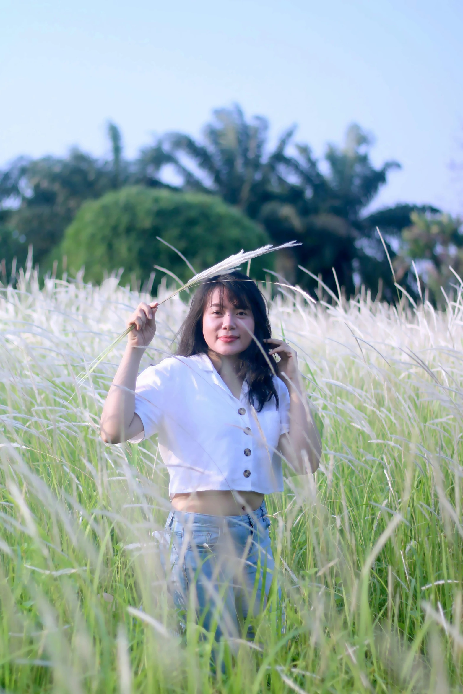 a woman posing in tall grass with a umbrella