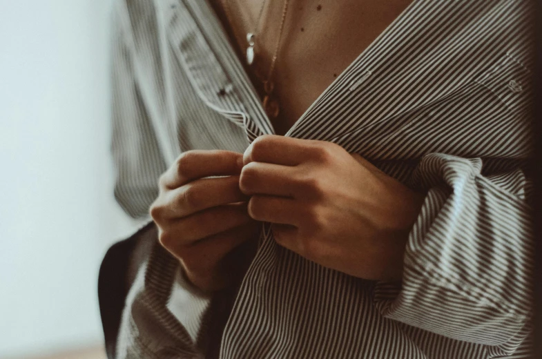 a man wearing a grey  shirt is tying his tie