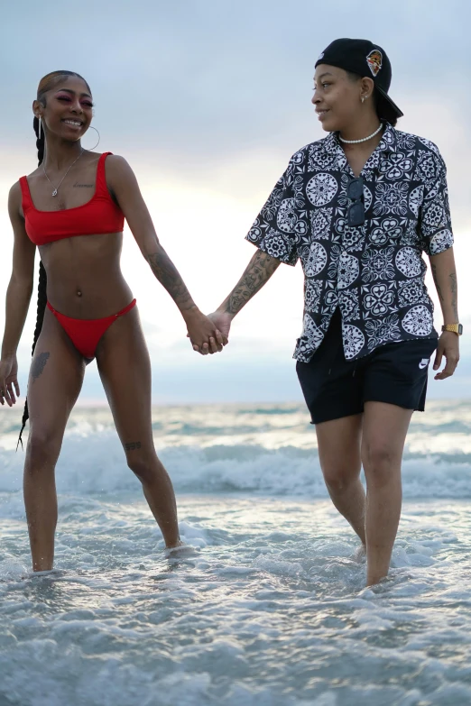 two women walking hand in hand in the ocean