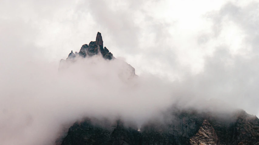 a rocky cliff with a mountain covered in low lying clouds