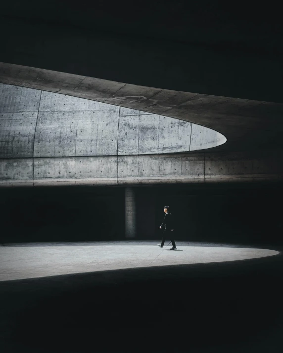 a man walking in the dark under a large structure