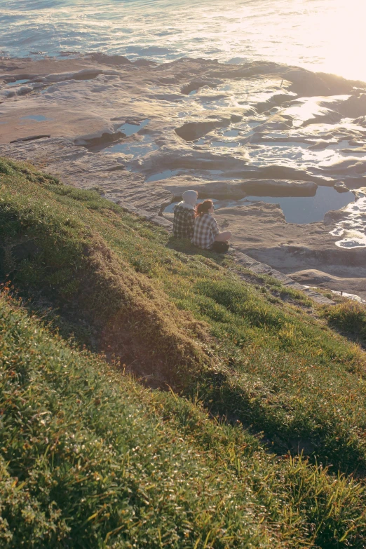 two people on a grassy hill overlooking the ocean