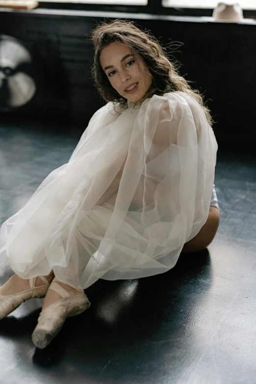 a woman poses with her legs apart while wearing ballet shoes