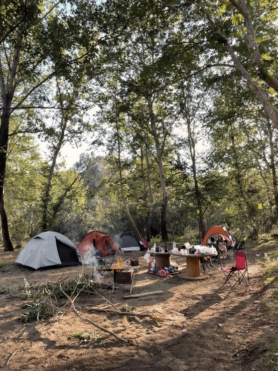 tents are sitting near trees and chairs while camping