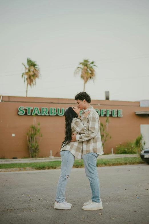 a couple standing outside of a starbucks and hugging