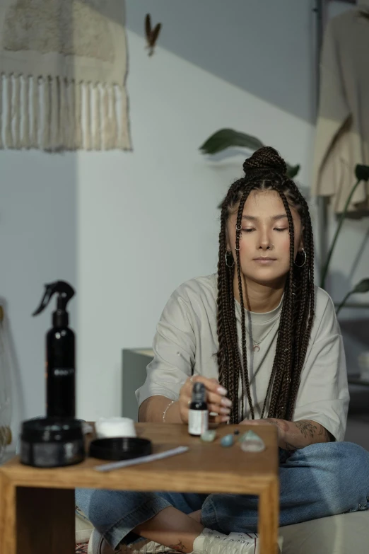 a woman sits on the floor while wearing dreadlocks