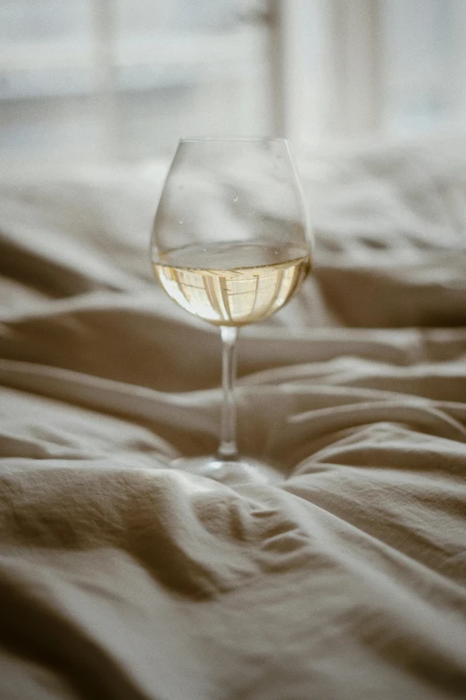 a glass of wine on top of a bed