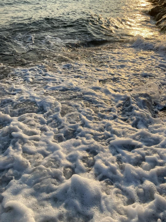 waves crashing on the sandy beach with sun in the background