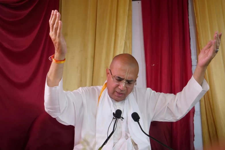 an older religious man holding his hands up with both hands