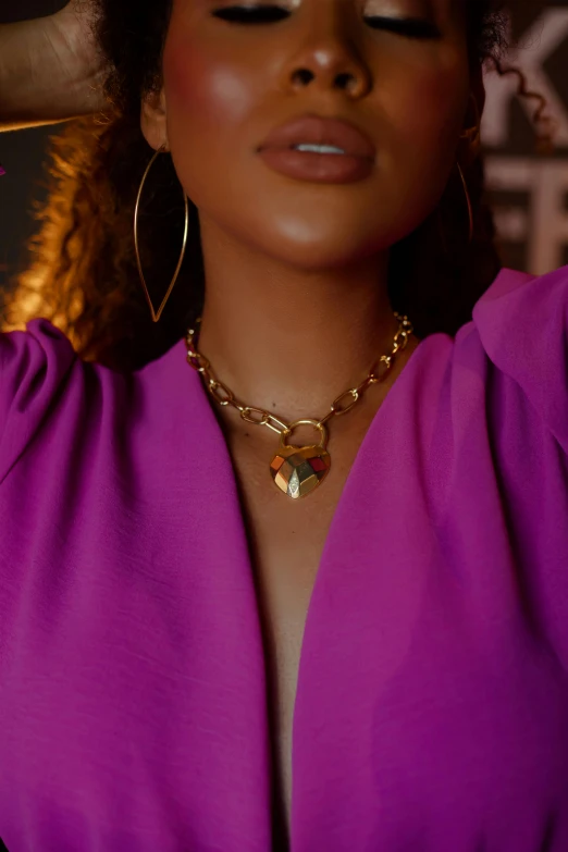 the woman is wearing a purple top and large gold hoops