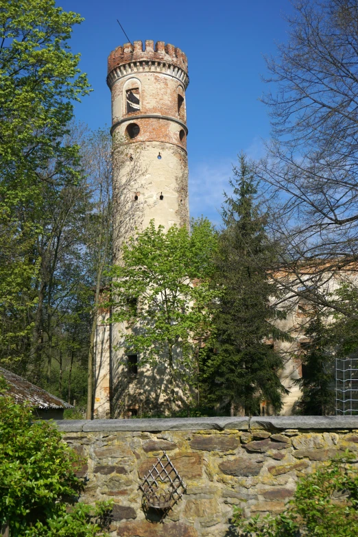 a stone wall and tower with trees behind it