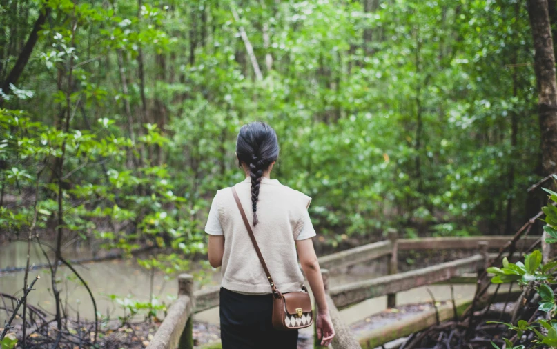 a girl on a trail walking across a wooden bridge