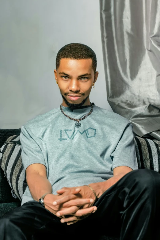 a man wearing a gray shirt is sitting on a black couch